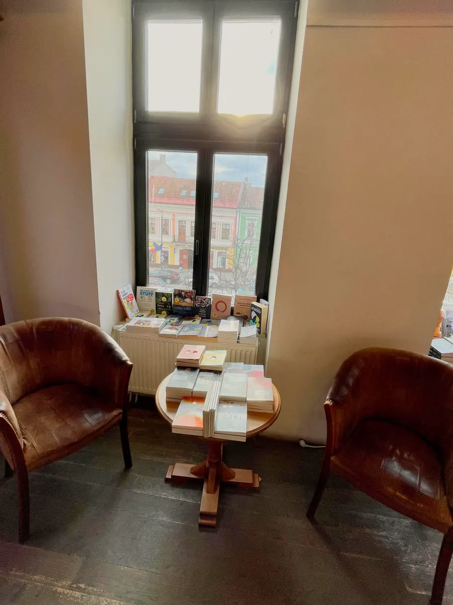 A quiet reading corner with two brown leather armchairs, a small round table of books and a tall window