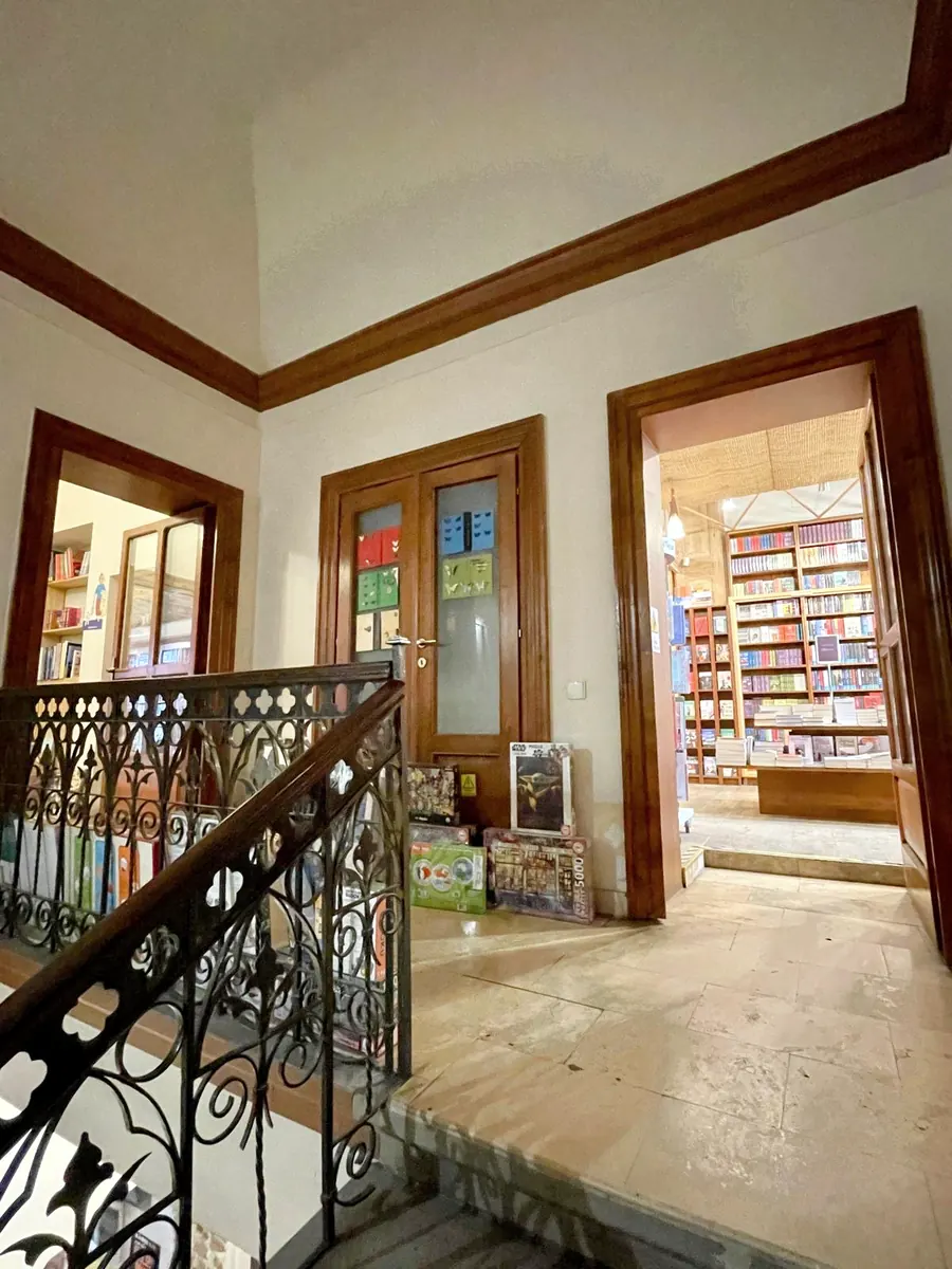 An architectural bookstore with an ornate staircase railing, wooden doorways and bookshelves